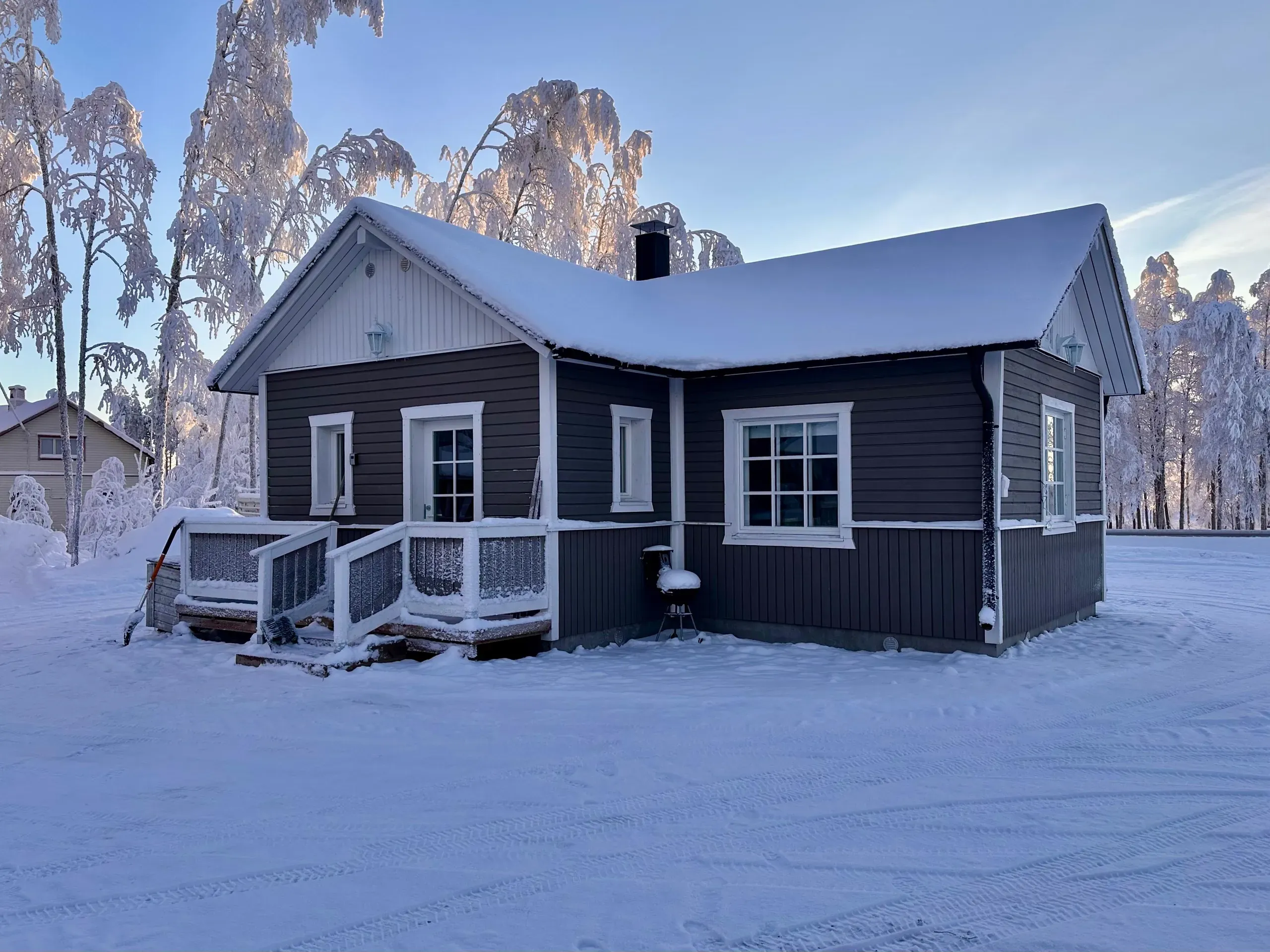 The Lepola log cabin among snow-covered birches at blue hour